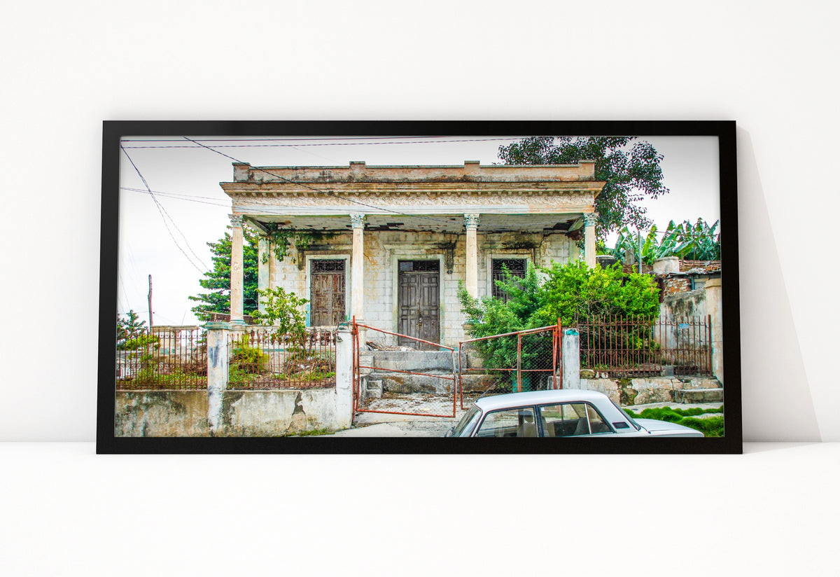Poster Cuba Villa 7 ingelijst, kleurenfoto van een verweerde villa met grijze zuilen en een oude witte auto voor het hek